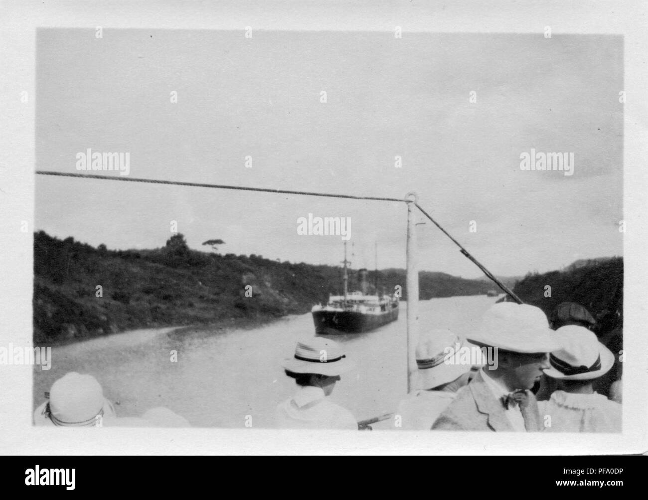 Fotografia in bianco e nero, girato da un angolo alto, mostra le teste delle persone in piedi sul ponte di una nave che naviga il Canale di Panama, con una seconda nave che naviga verso di loro e canal banche visibile su ogni lato, 1915. () Foto Stock