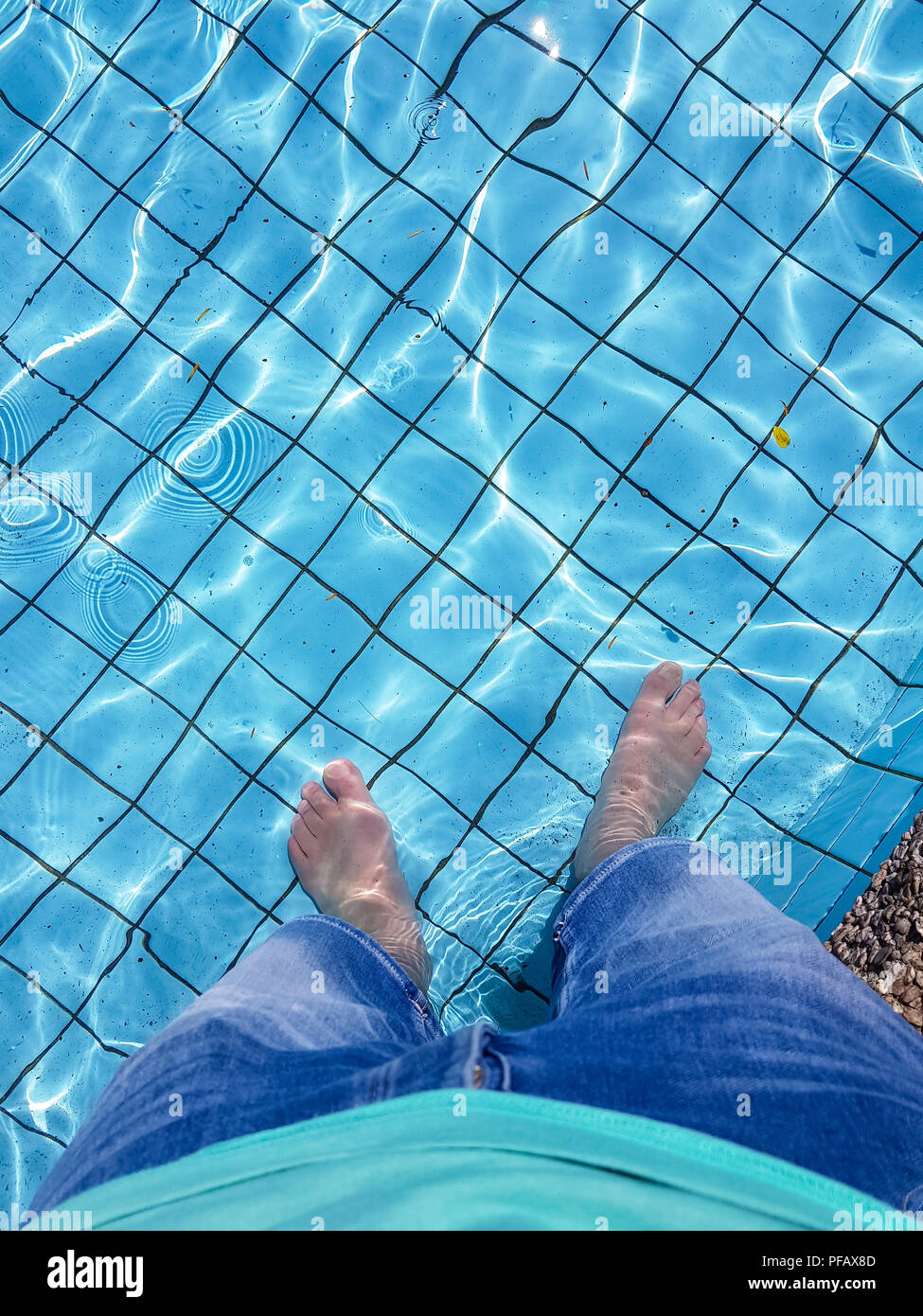 Piedini maschio con l'abbronzatura della pelle immersione in piscina Foto Stock