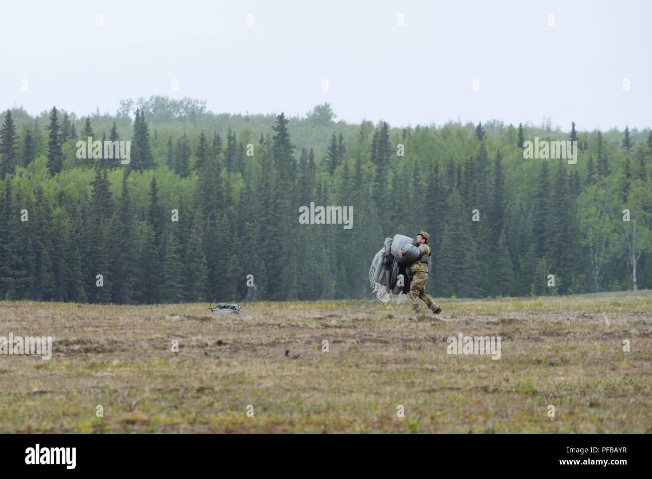 Un aviatore assegnati al 3° aria supportano operazioni squadrone recupera il suo paracadute dopo il salto da un esercito di Alaska National Guard UH-60 Black Hawk elicottero durante il volo in formazione di base comune Elmendorf-Richardson, Alaska, 30 maggio 2018. Avieri dal 3° ASOS, Soldati assegnati a U.S. Esercito Alaska e Alaska esercito nazionale Guard aviatori con il primo battaglione, 207th reggimento di aviazione, condotto la joint airborne jump training per aumentare l'interoperabilità e mantenere la disponibilità di missione. Foto Stock