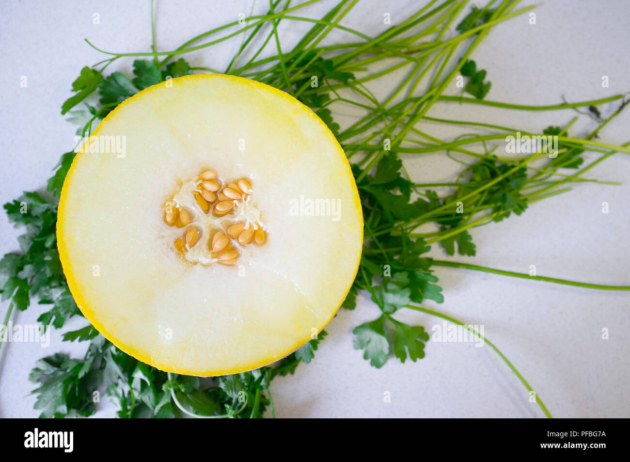 La metà di un Melone Galia su sfondo di prezzemolo. Primo piano Foto Stock