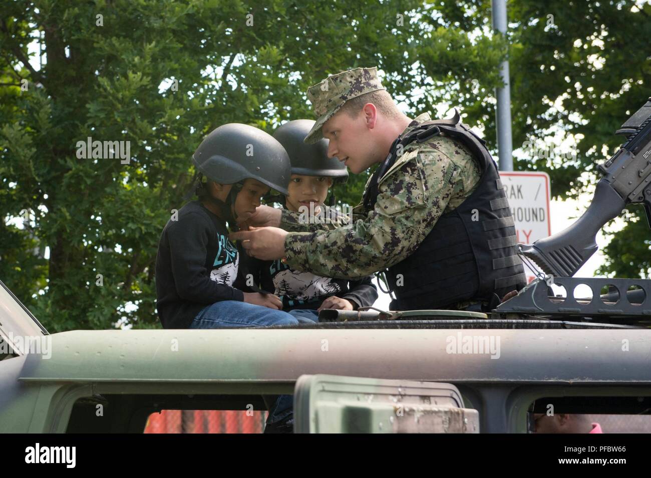 Everett, Washington. (02 giugno 2018) Master-at-Arms marinaio Gaige Hoffman aiuta a Everett abitanti indossano il casco ad alta mobilità veicolo multiuso (HMMV) e M240 mitragliatrice visualizzazione statica durante l'Everett la celebrazione dell anniversario. La città ha collaborato con varie organizzazioni per il suo centoventicinquesimo anniversario evento di celebrazione. Foto Stock