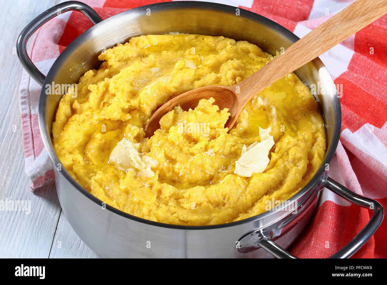 Deliziosa polenta calda porridge con burro fuso in padella con il cucchiaio  di legno, asciugamano da cucina sul tavolo bianco, autentica ricetta  italiana, vista da sopra Foto stock - Alamy