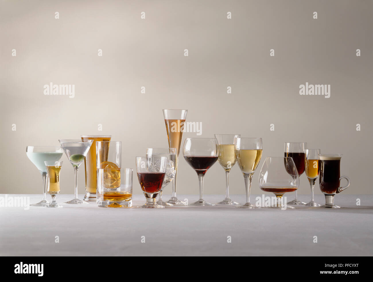 Vasto assortimento di bevande alcoliche visualizzati nel loro servizio specializzato occhiali, disposti in una fila, vista frontale. Foto Stock