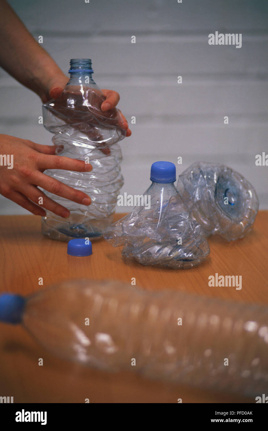 Le bottiglie di plastica vuote essendo mano-compressa, vista laterale. Foto Stock