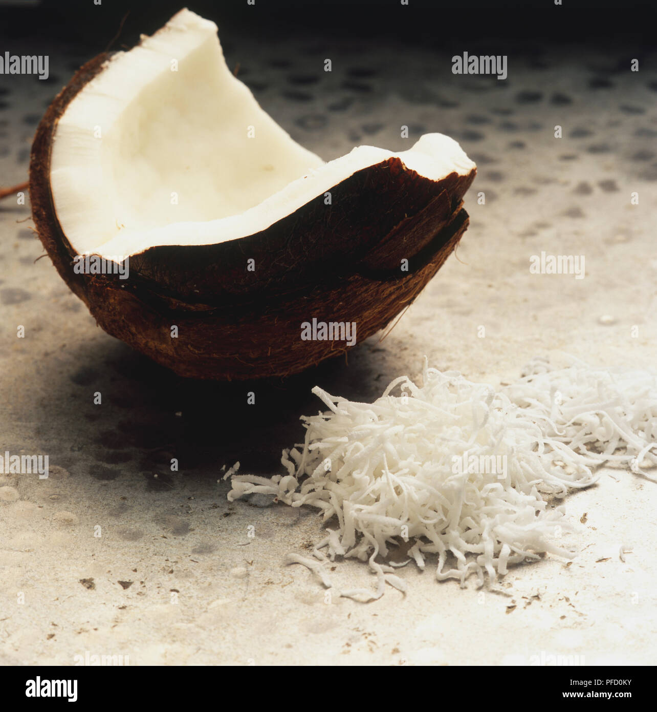 Il Cocos nucifera, noce di cocco, incrinature del guscio contenente latte, e grattugiato carne bianca. Foto Stock