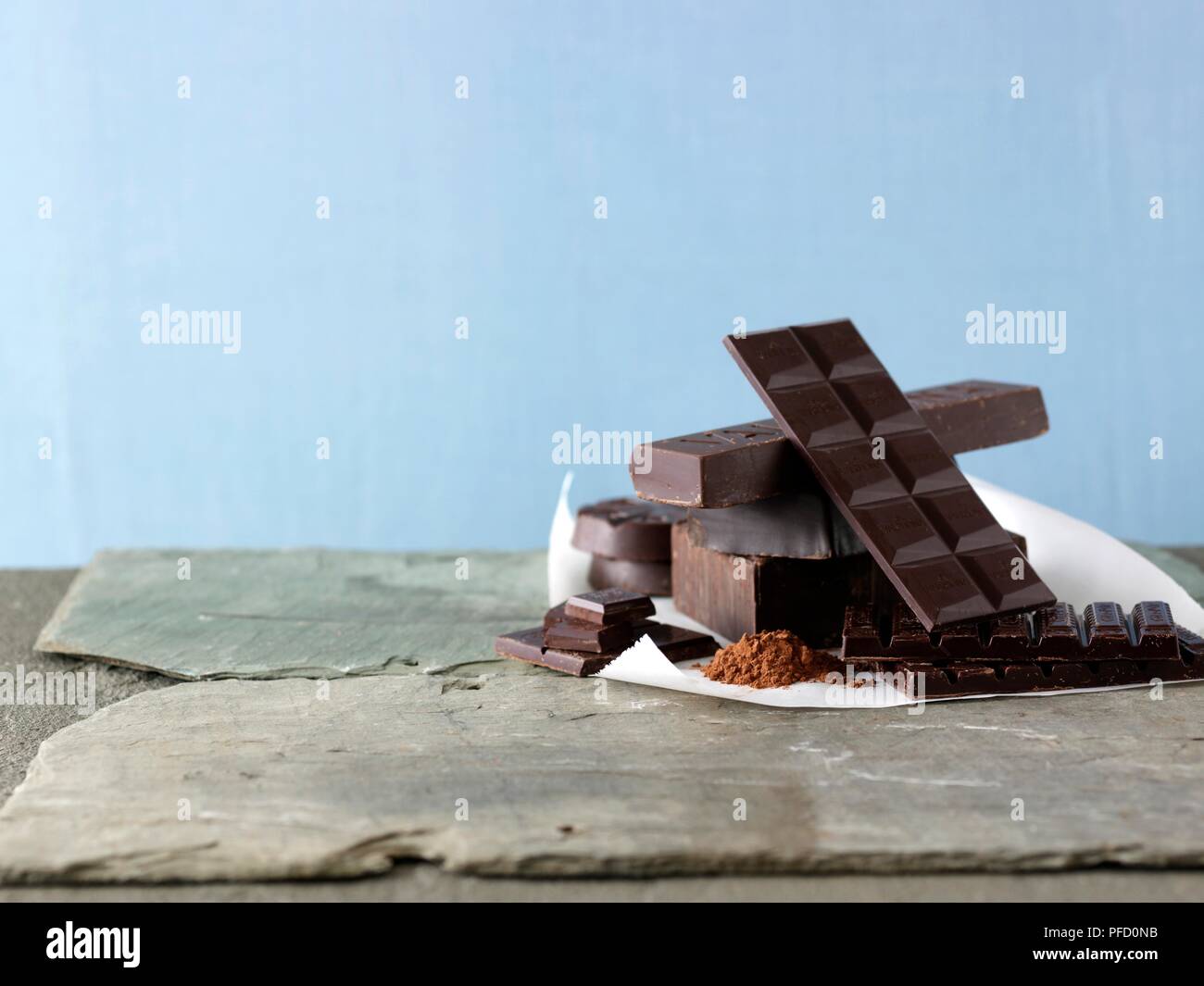 Impilate le barre di cioccolato fondente e cioccolato grattugiato disposti su piastrelle di ardesia Foto Stock