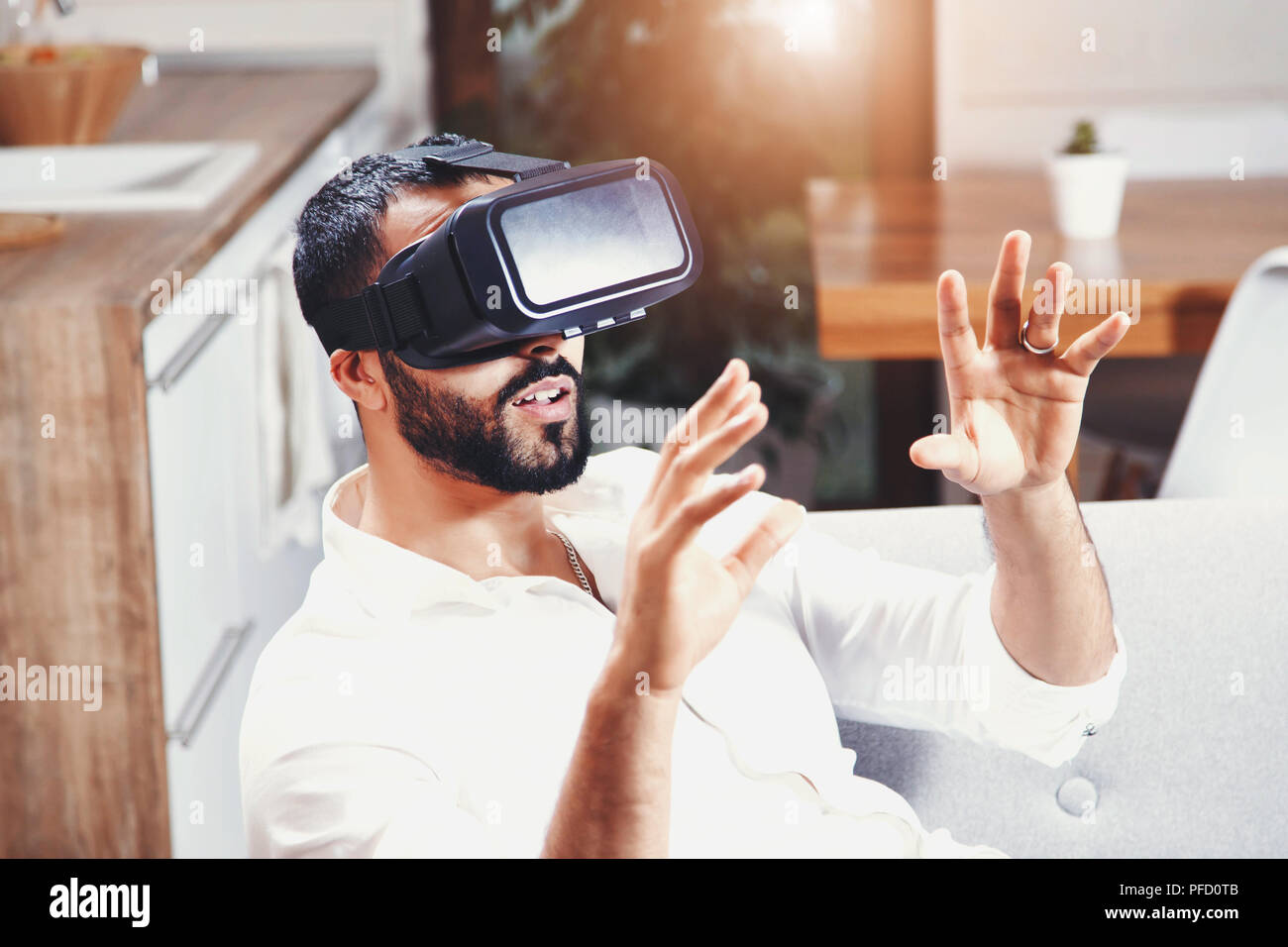 Felice multiculturale uomo barbuto prendere l'esperienza utilizzando VR-cuffia bicchieri di realtà virtuale a casa Foto Stock