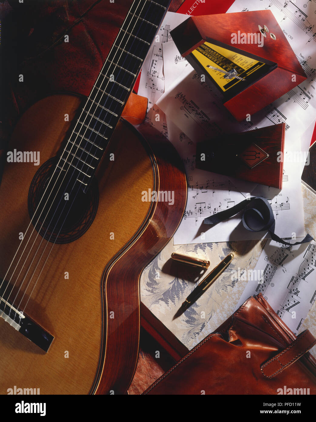 Chitarra acustica, notazione musicale, metronomo, penna, custodia in pelle, vista in elevazione. Foto Stock