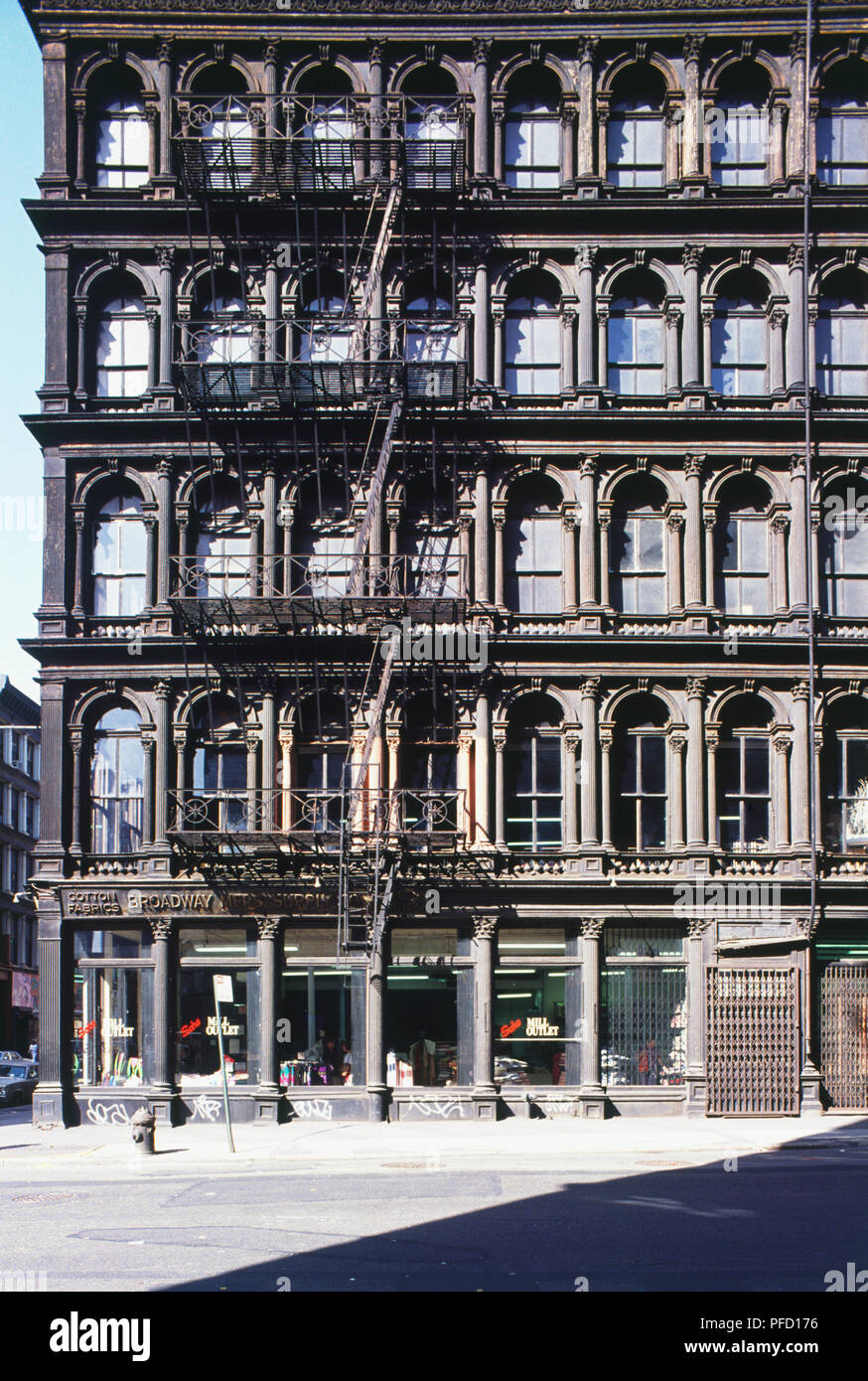Stati Uniti d'America, New York, quattro piani di edificio ad angolo con scala esterna, finestre incorniciate da colonne ornamentali, negozio di tessuti al piano terra. Foto Stock