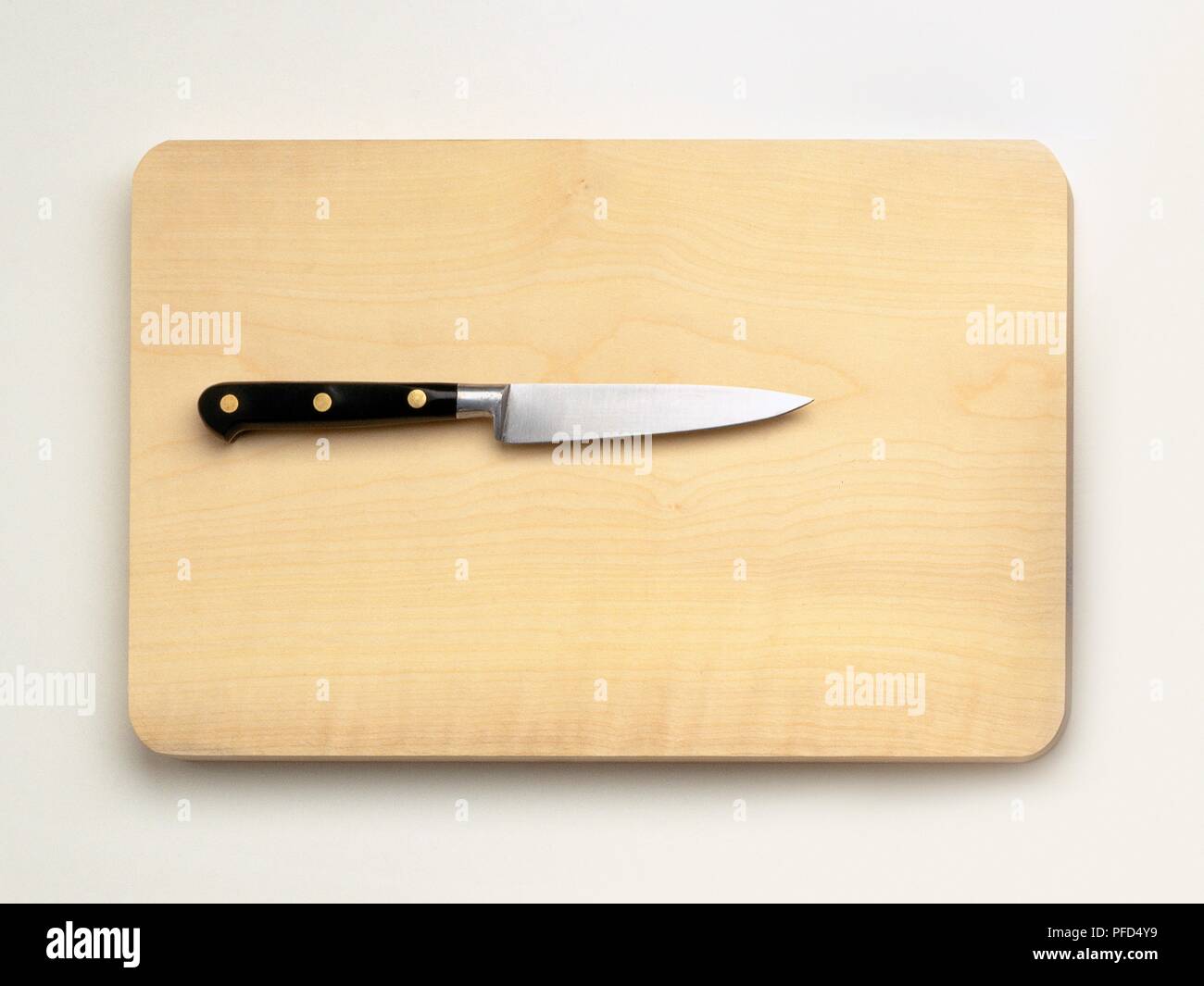 Piccolo coltello seghettato sul tagliere di legno Foto Stock