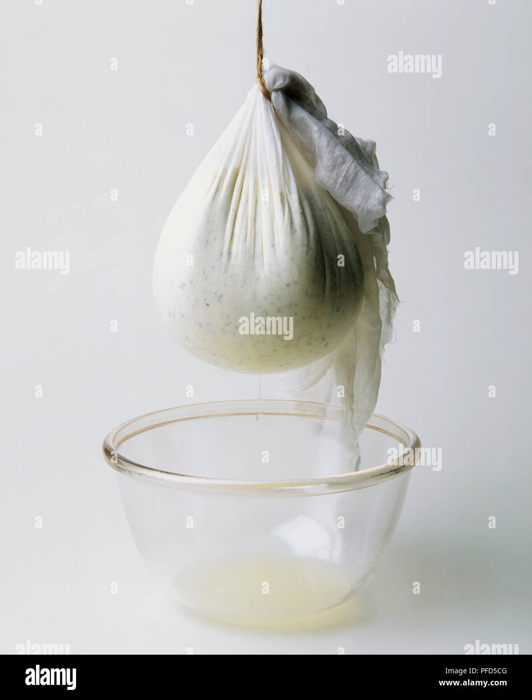 Mussola sacchetto contenente yogurt base di formaggio a pasta molle (labna), sospesa al di sopra di ciotola Foto Stock