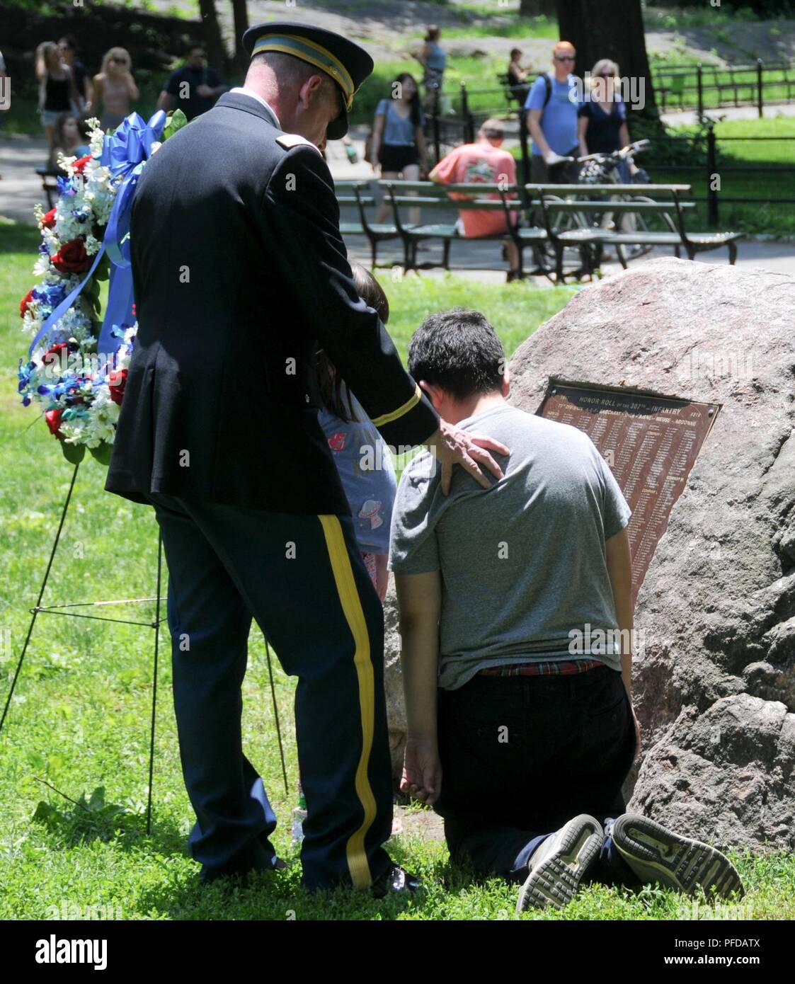 Un soldato e bambini visitano la lapide a seguito della 77a Divisione di Fanteria Commemorazione Il 9 giugno presso il 307th Reggimento di Fanteria Memorial Grove nel Central Park di New York. La manifestazione annuale è ospitato dalla fanteria 307th Società Reduci e rende omaggio a tutti i soldati del 77th che hanno dato la loro vita in servizio dal 1917. Foto Stock