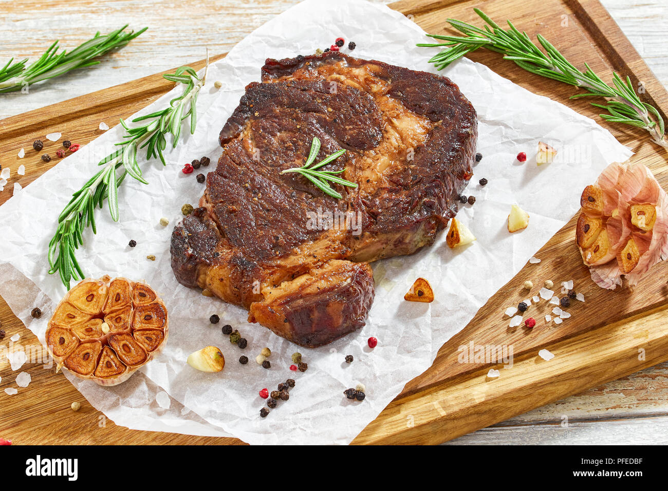 Delizioso caldo bistecca di manzo carne succosa bistecca fritti in padella  di ferro con rosmarino, olio d'oliva, spicchi di aglio, il burro e il pepe,  close-up, vista da sopra Foto stock -