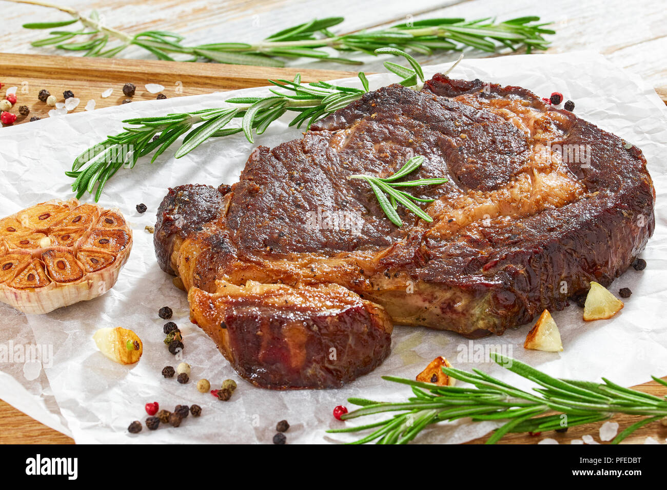 Delizioso caldo bistecca di manzo carne succosa bistecca fritti in padella  di ferro con rosmarino, olio d'oliva, spicchi di aglio, il burro e il pepe,  close-up, vista da sopra Foto stock -