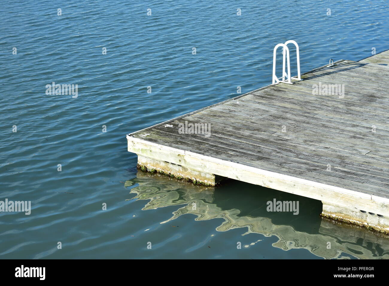 Svuotare pontile galleggiante con la scala di metallo della ringhiera dipinto di bianco in legno e pavimento in ardesia. Foto Stock