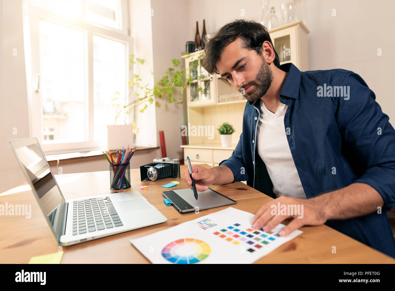 Graphic designer che lavora sulla tavoletta digitale. Libero professionista a lavorare a casa. Foto Stock