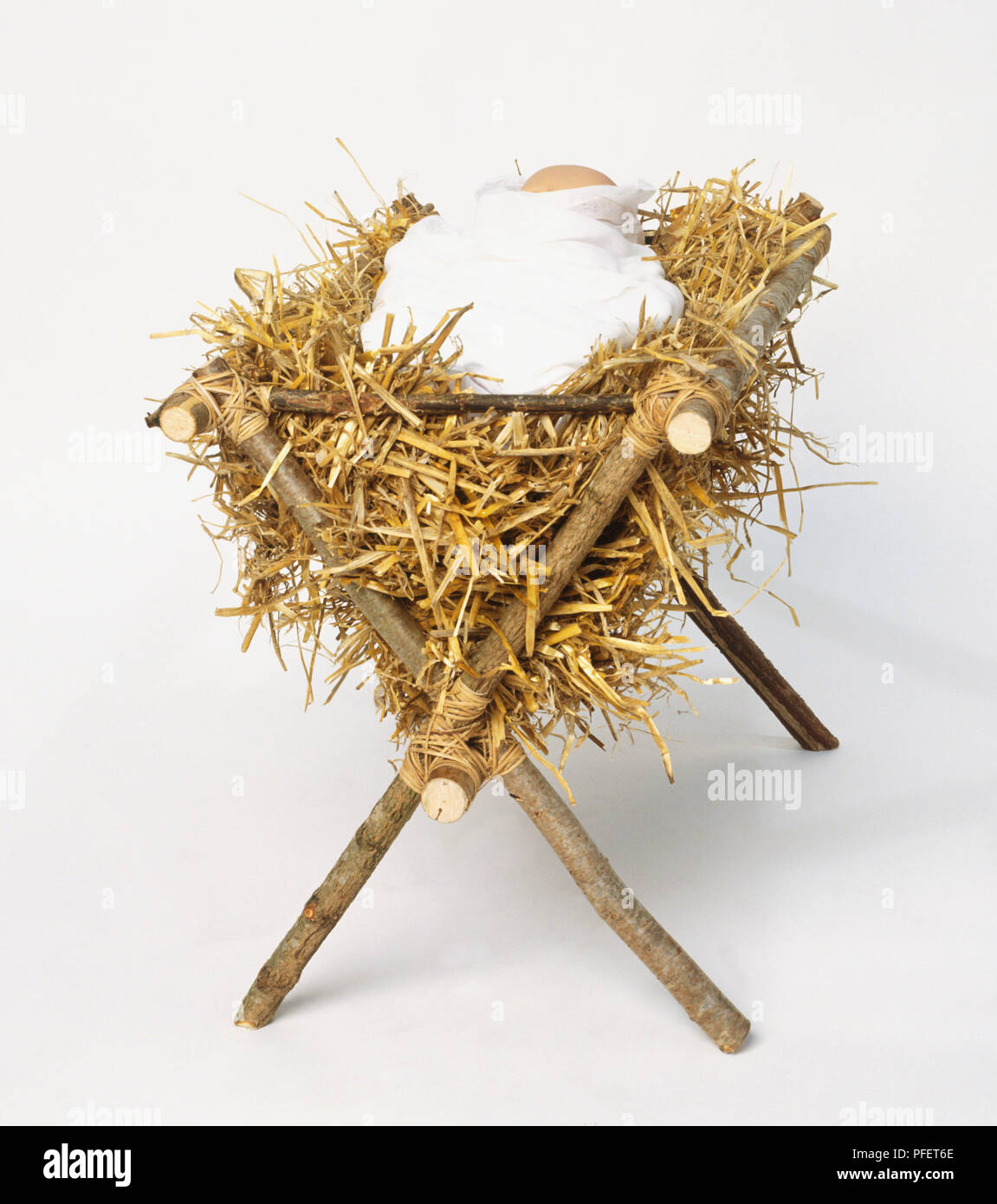 Baby doll avvolto in fasce e deposto in una mangiatoia come parte di una Natività giocare Foto Stock