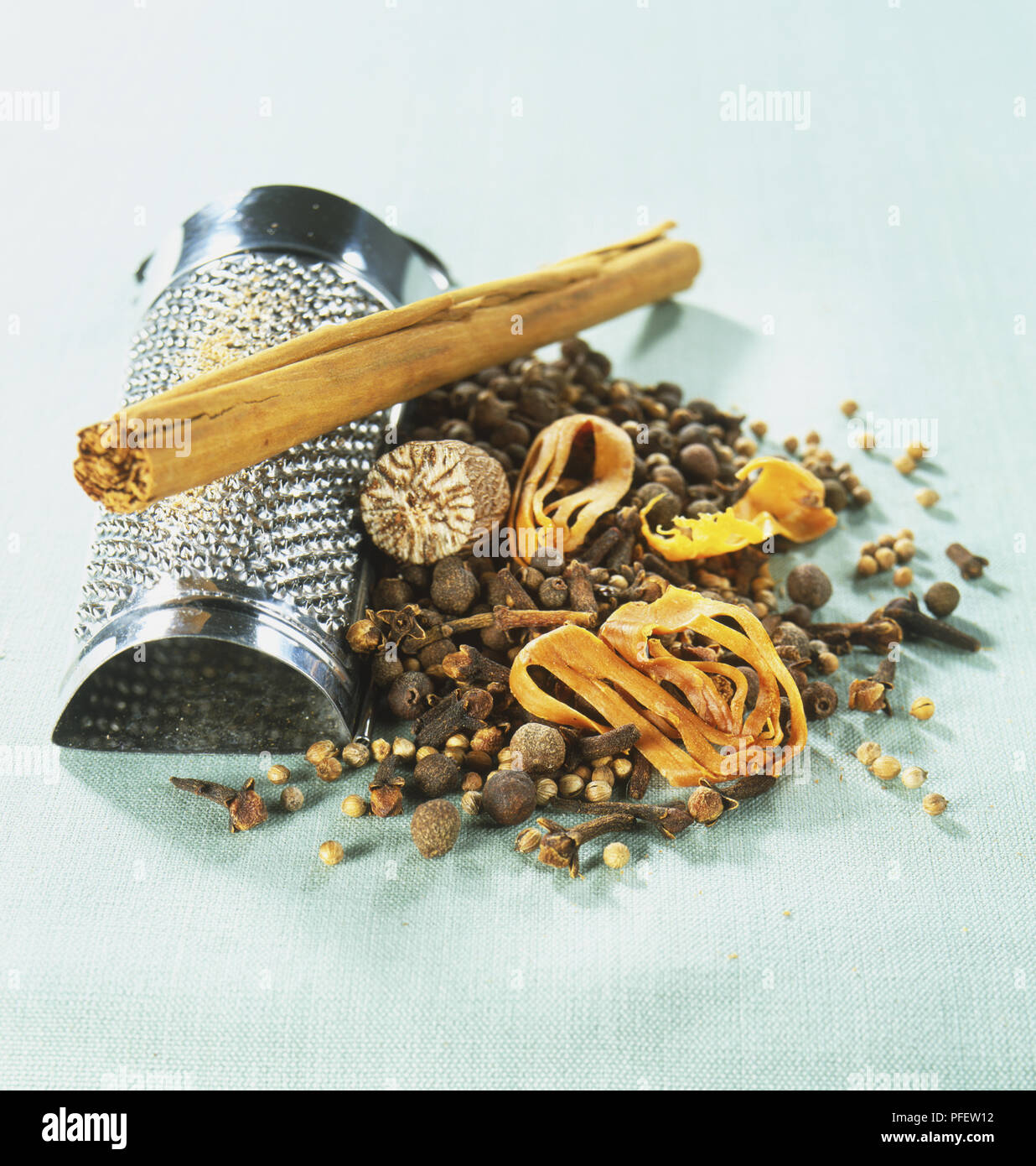 Spezie miste ingredienti, compresi il pepe di Giamaica in grani, semi di coriandolo, chiodo di garofano, macis, noce moscata, la cannella quills e grattugia in metallo Foto Stock