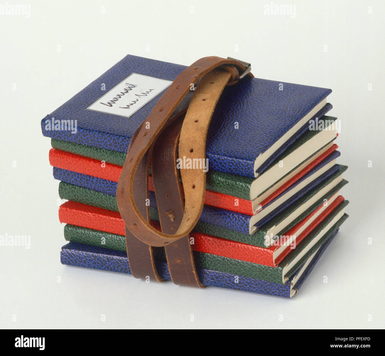 Pila di libri con colorate coperture in pelle legati insieme marrone con cintura in cuoio, vista laterale Foto Stock