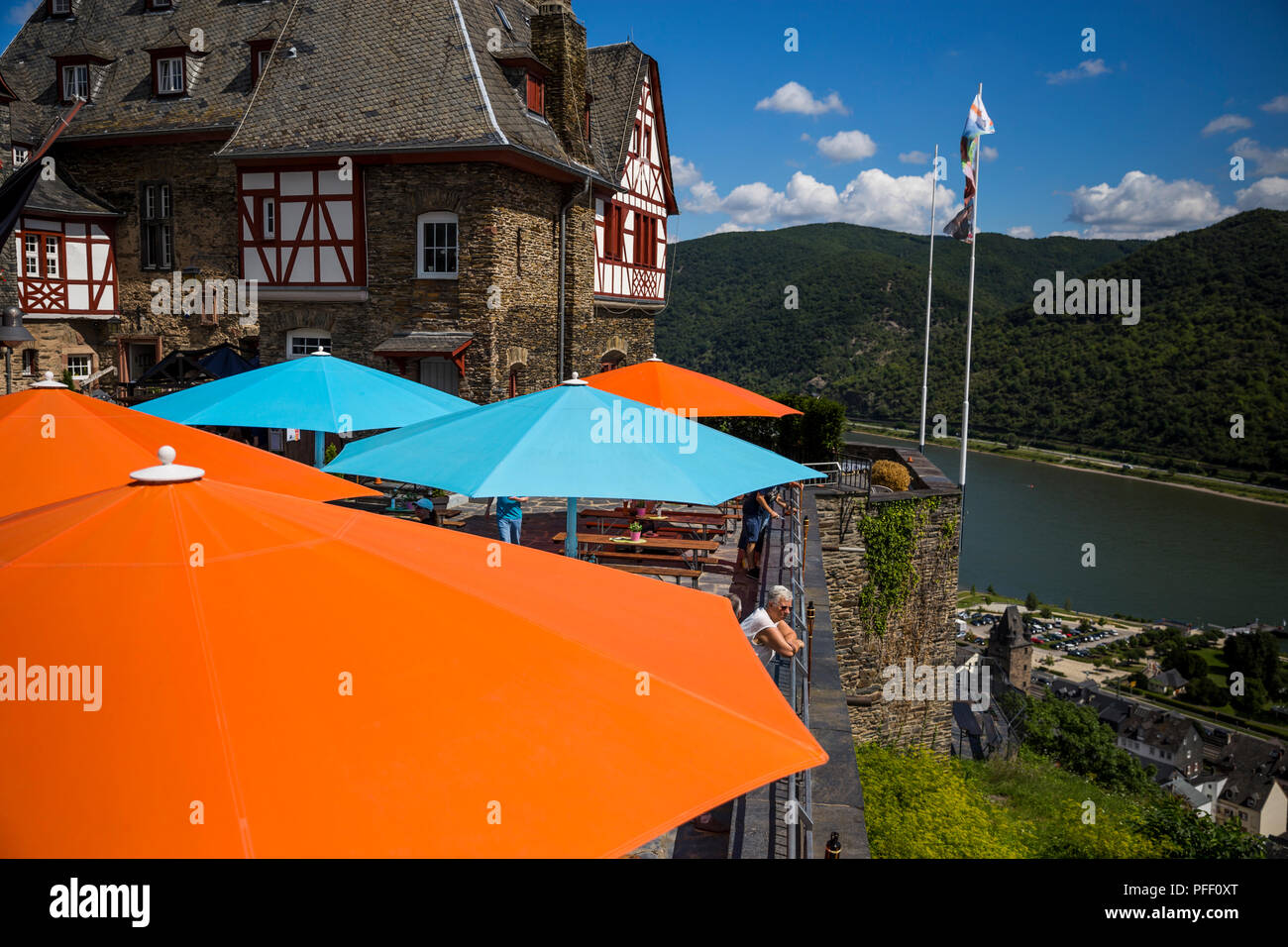 Un turista si affaccia sul Reno da sotto gli ombrelloni colorati al Castello Stahleck a Bacharach, Germania. Foto Stock