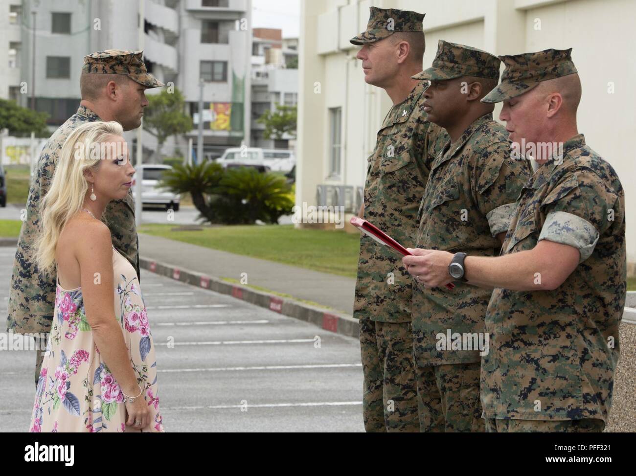 Sgt. Il Mag. James N. Calbough, sergente maggiore del 3° Marine Logistics Group, legge il Navy e Marine Corps encomio medaglia citazione durante una cerimonia in onore di Gunnery Sgt. Scott M. Dahn e sua moglie, aprile B. Dahn, Giugno 12, 2018 a Camp Kinser, Okinawa, in Giappone. Il giovane è stato premiato da Col. Ronald C. Braney, il comandante della terza MLG, per le loro azioni eroiche al punto Maeda, Okinawa, in Giappone, 20 maggio 2018. Un turista da Hong Kong, Ching-Yi Sze, è stato panico subacquea, aveva rimosso il suo regolatore aria e stava cominciando a prendere in acqua quando Dahn vennero in suo aiuto. Egli ha fornito la sua con ox Foto Stock