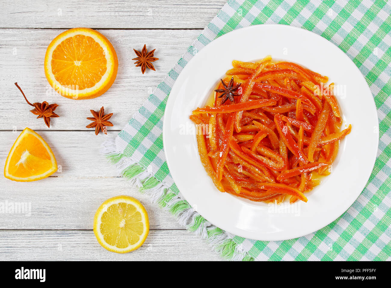 Deliziosi dolci fatti in casa arancia candita e bucce di limone sulla piastra bianca sul tavolo di legno con le metà di arancia e limone su sfondo, vista da sopra Foto Stock