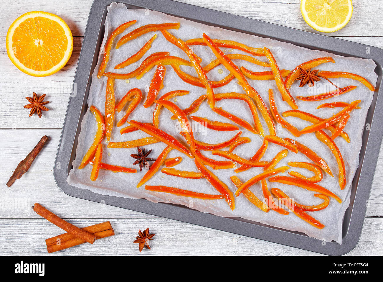 Deliziosi dolci fatti in casa arancia candita e bucce di limone cotta sulla teglia con la cannella e la noce moscata e anice stella. metà di arancia e limone su legno Foto Stock