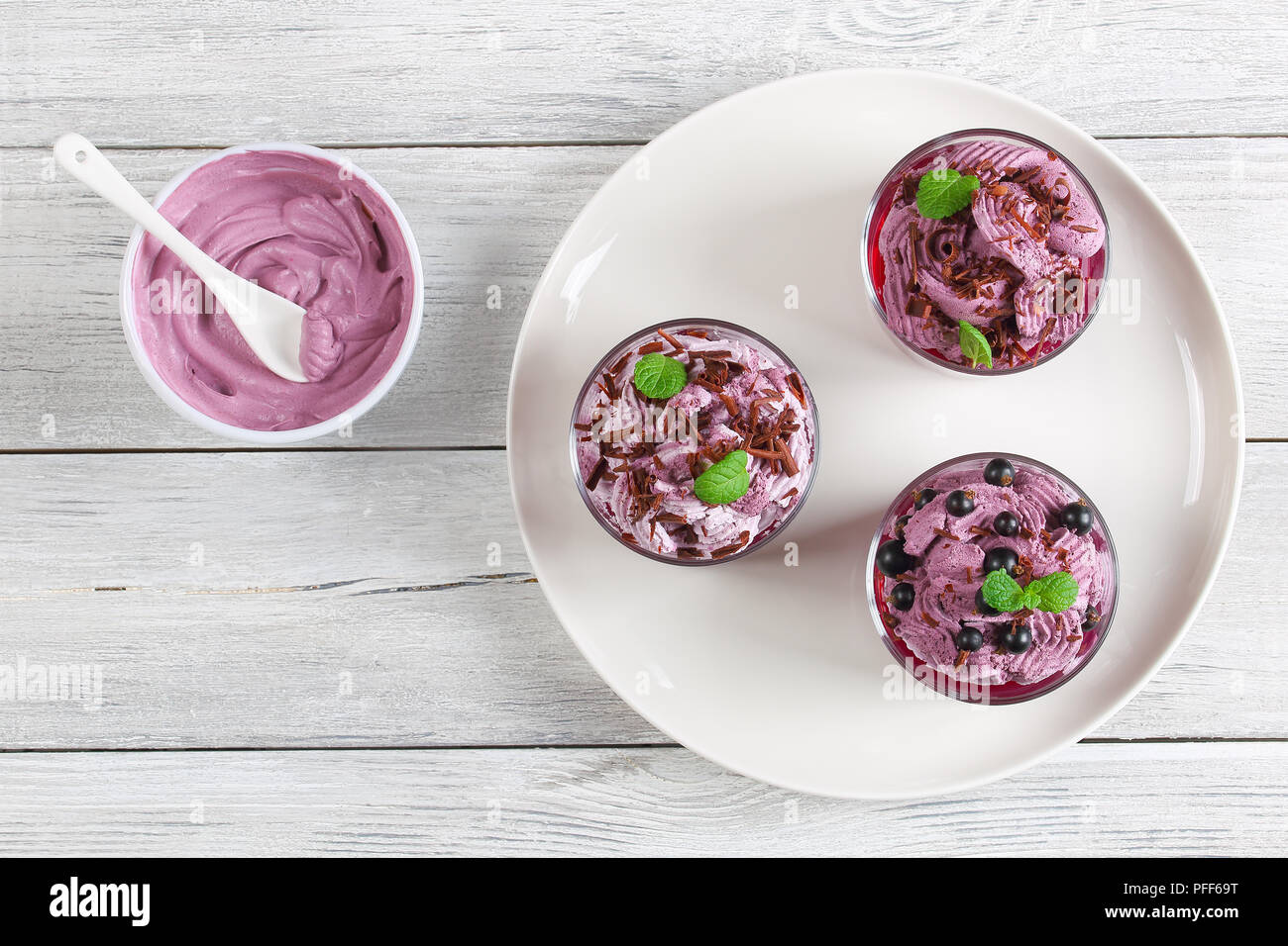 Deliziosa estate sano gelato dessert di ribes nero decorato con foglie di menta in bicchieri di vetro sulla piastra. Congelati Panna ricotta Yogurt mous Foto Stock