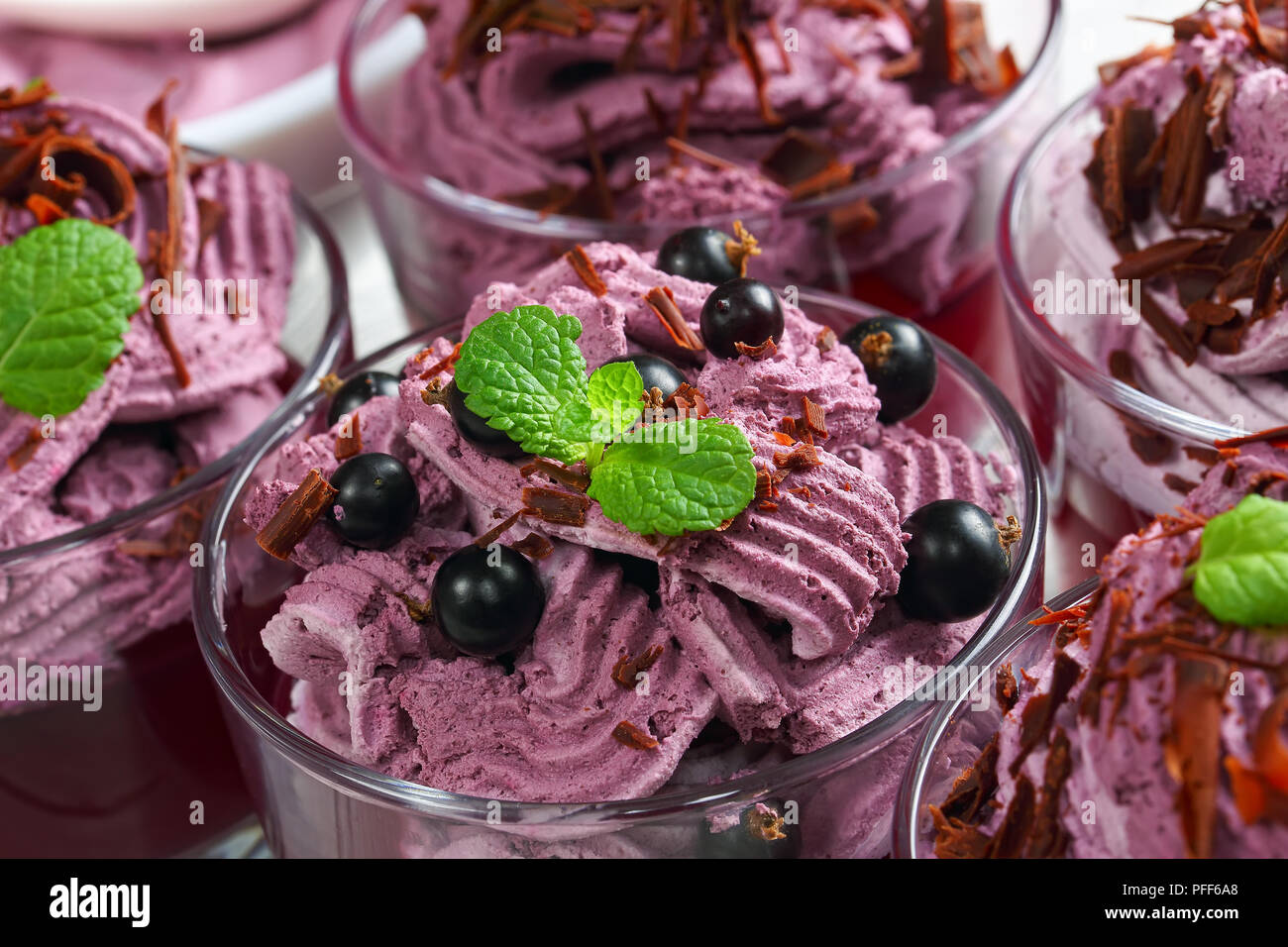 Layered gelato dessert di bacche di ribes nero , la ricotta e lo yogurt decorato con foglie di menta e spolverati con scaglie di cioccolato in vetro cu Foto Stock