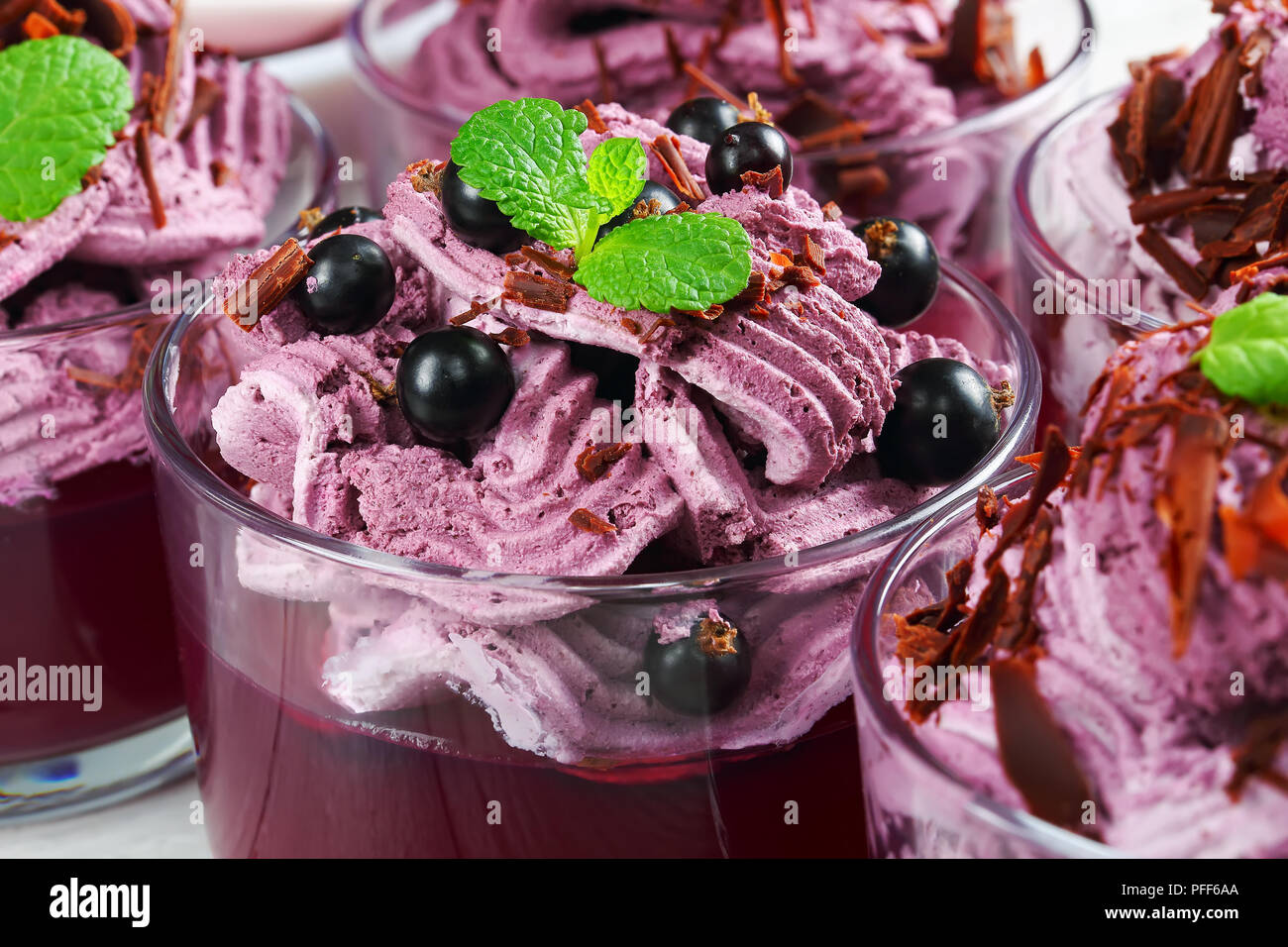 Layered jelly e gelato dessert di bacche di ribes nero mousse di ricotta e yogurt decorato con foglie di menta e spolverate con il cioccolato Foto Stock