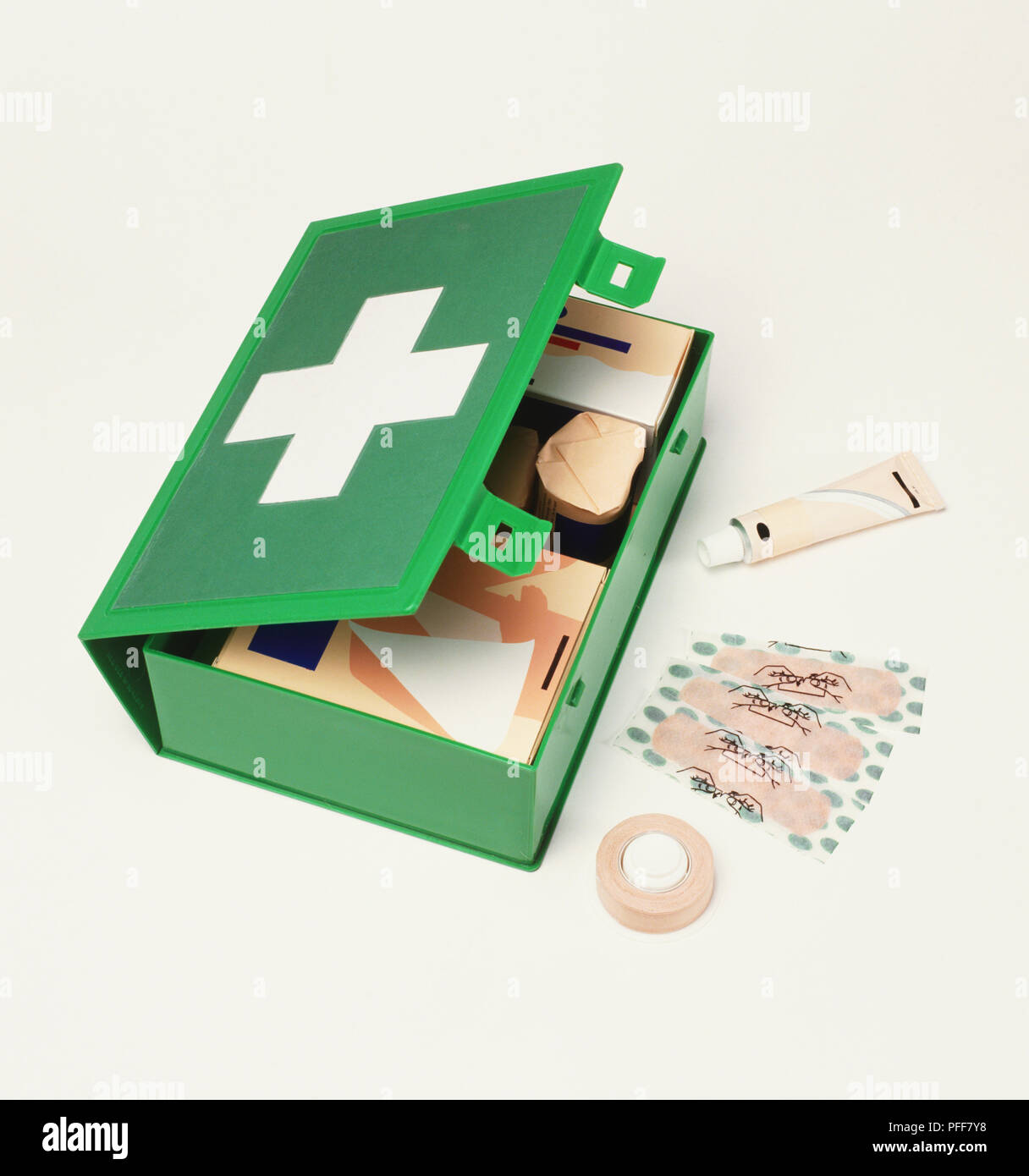 Green kit di primo soccorso caso, cerotti, tubo di metallo, rotolo di nastro medico, vista in elevazione. Foto Stock