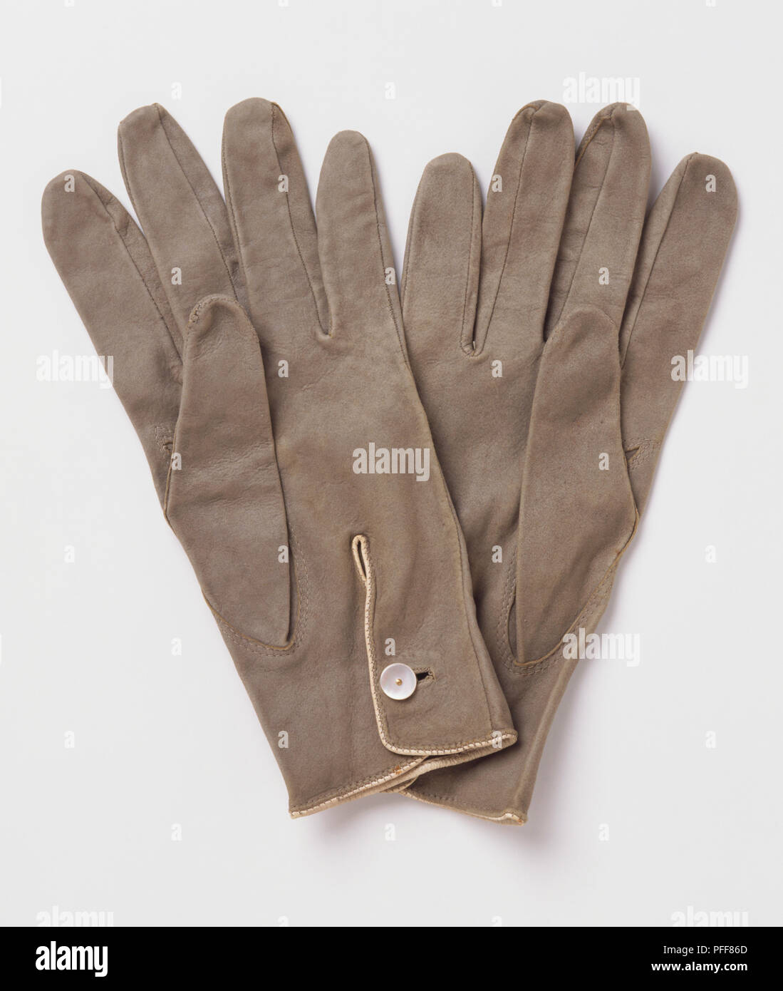 Coppia di grigio indossato i guanti di cuoio, fissata con i pulsanti bianchi, fodera beige parzialmente visibile Foto Stock