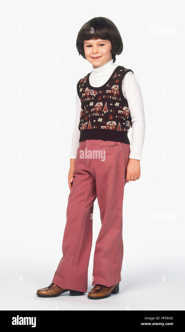 Ragazzo con blow-capelli secchi indossando maglietta stretta e maglione di lana, pantaloni svasatura dal ginocchio al hem e scarpe con tacco Foto Stock