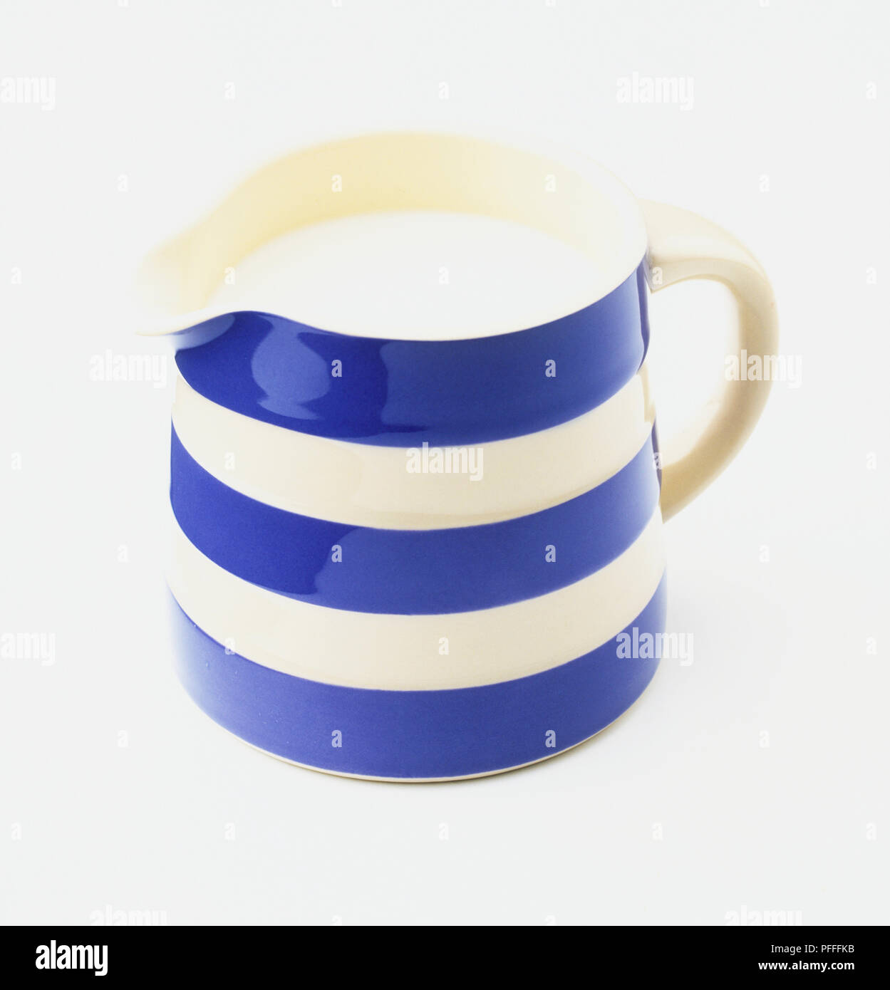 Un blu e bianca a strisce brocca contenente latte. Foto Stock