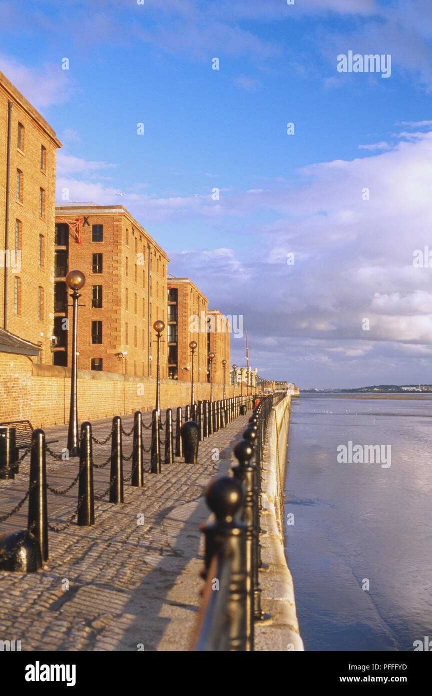 Gran Bretagna, Inghilterra, Liverpool, Albert Dock Quay accanto al fiume Mersey. Di bassa altezza di edifici in mattoni e muratura in mattoni passeggiata lungo il fiume. Foto Stock