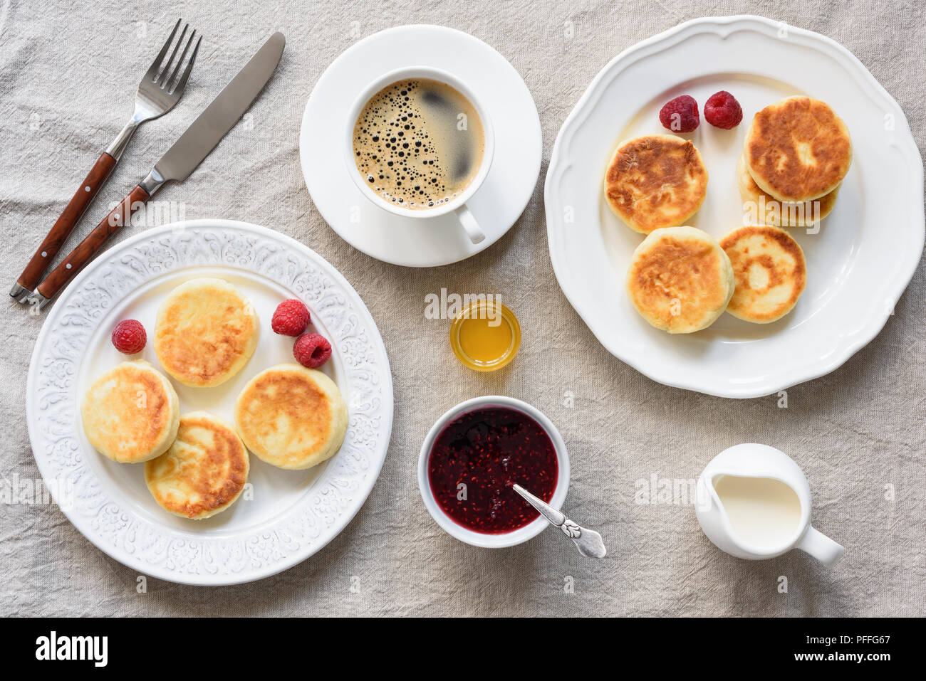 Tavolo per la colazione Cottage Cheese Pancakes, caffè, panna, miele e marmellata. Sfondo tessili. Una gustosa prima colazione, syrniki. Cucina russa Foto Stock