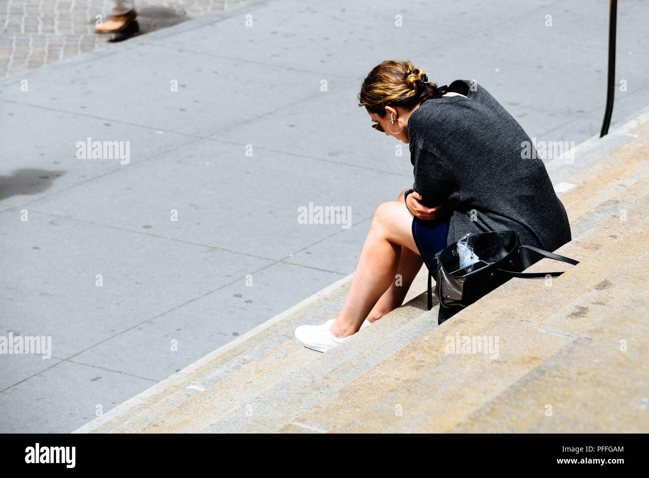 La città di New York, Stati Uniti d'America - 20 Giugno 2018: donna non identificato con cuffie seduti sui gradini della sala federale edificio di Wall Street Foto Stock