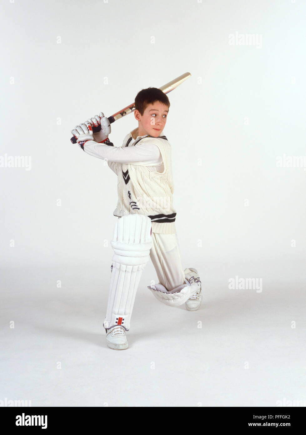 Ragazzo con il cricket bat sollevate dietro la testa Foto Stock