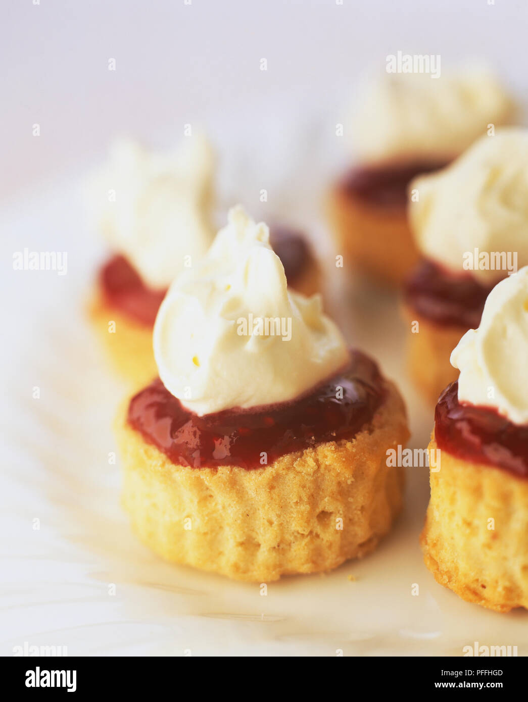 Tiny Devonshire scones rabboccato con lampone conservare e crema. Foto Stock