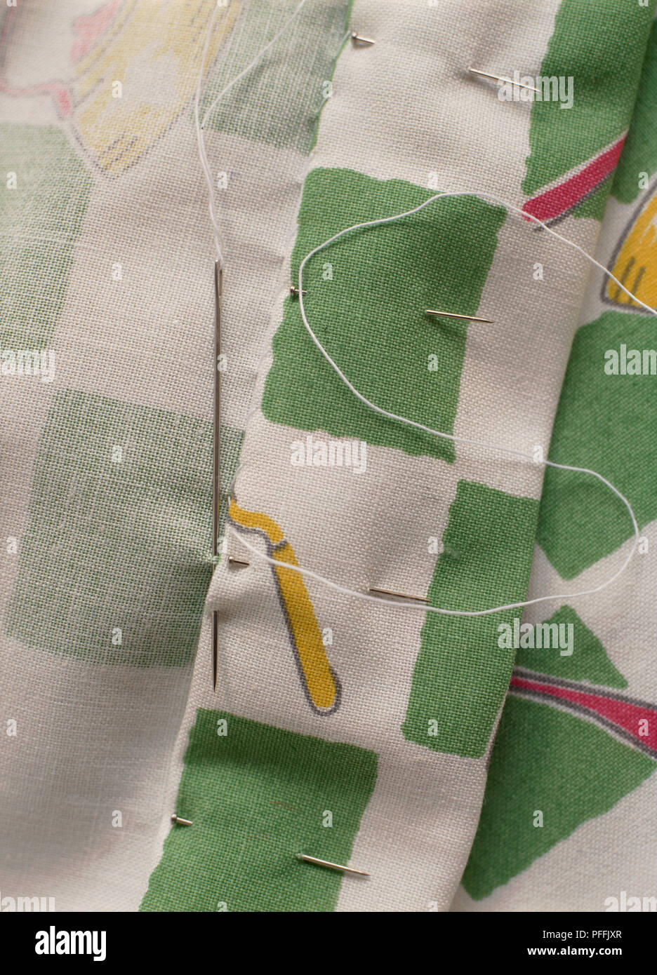 La cucitura del lembo di verde e tende bianche, ago con filo bianco con cuciture, perni orlo di tenuta in posizione. Foto Stock