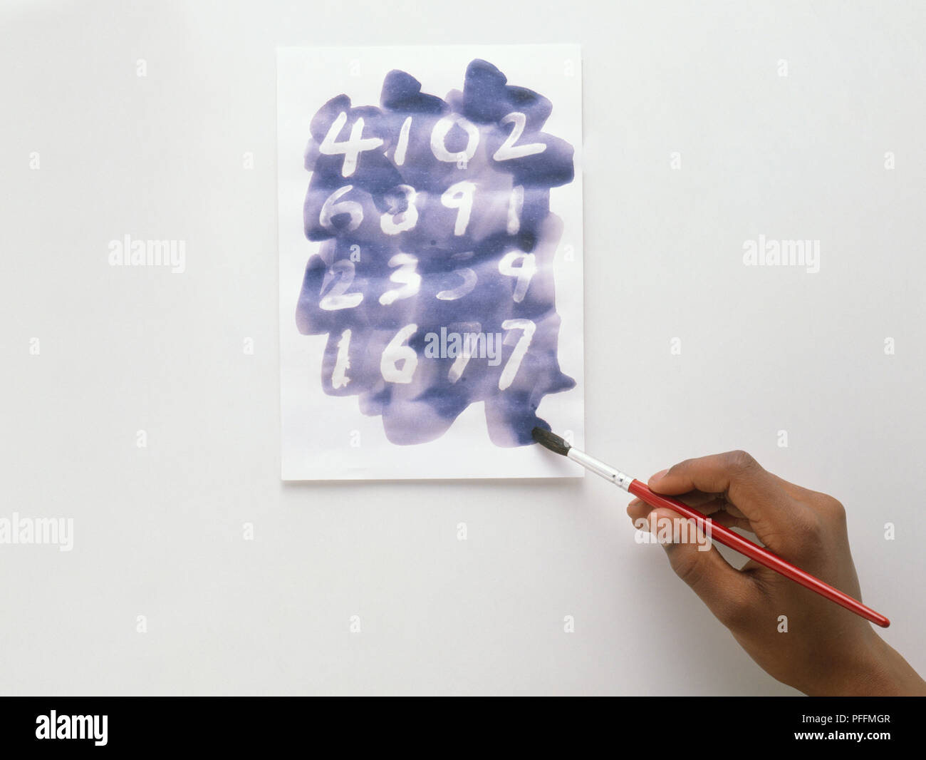 Bambino con lo strumento Pennello e inchiostro blu per rendere invisibili i numeri vengono visualizzati sulla carta Foto Stock