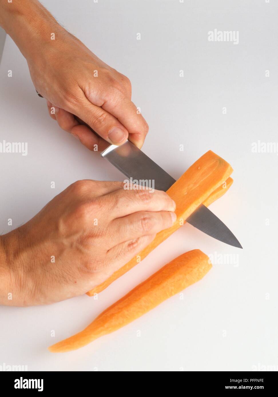 Il taglio di una carota nel senso della lunghezza Foto Stock
