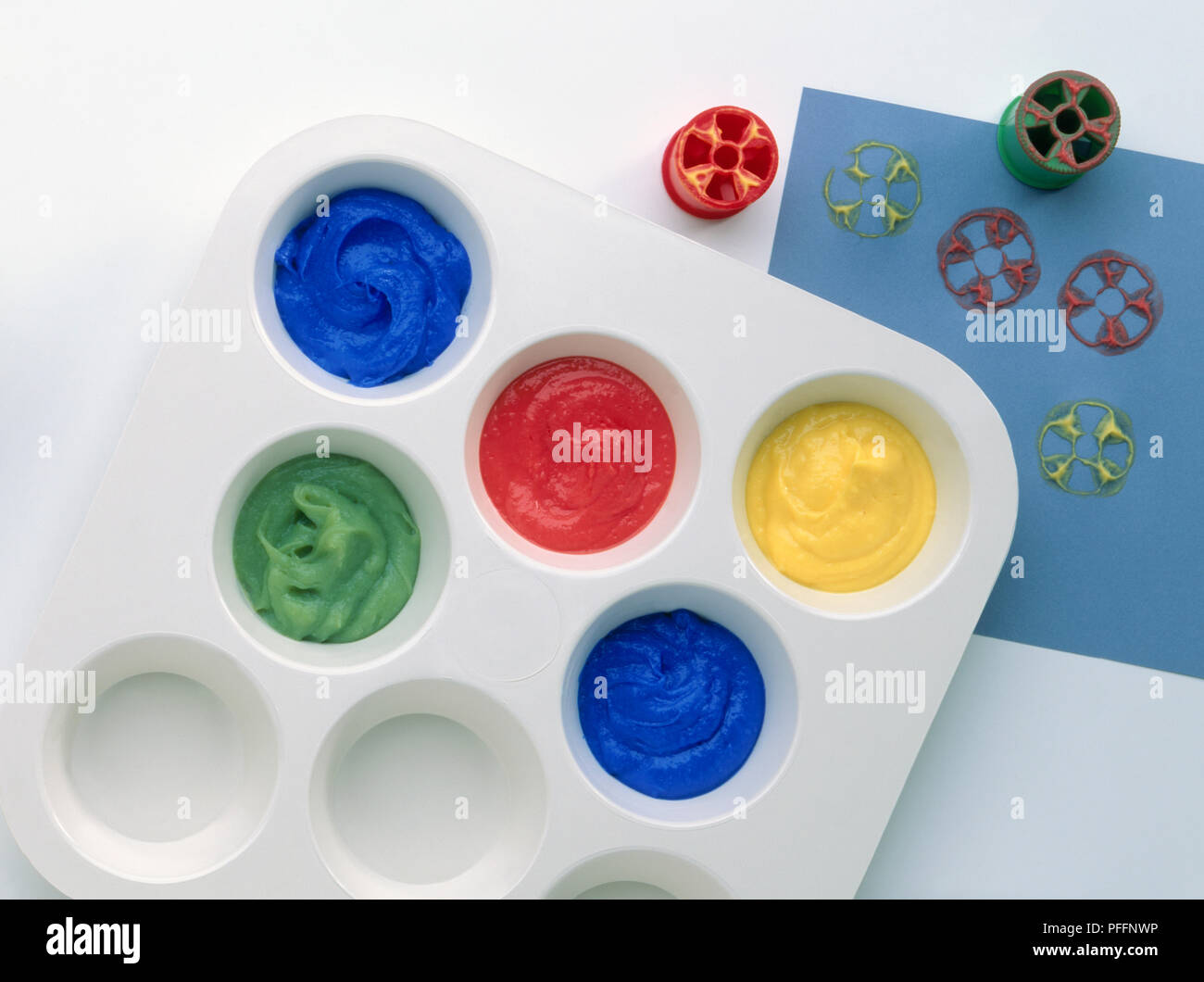 Casella di vernice e bobina di cotone stampe su carta blu, close-up, vista da sopra Foto Stock