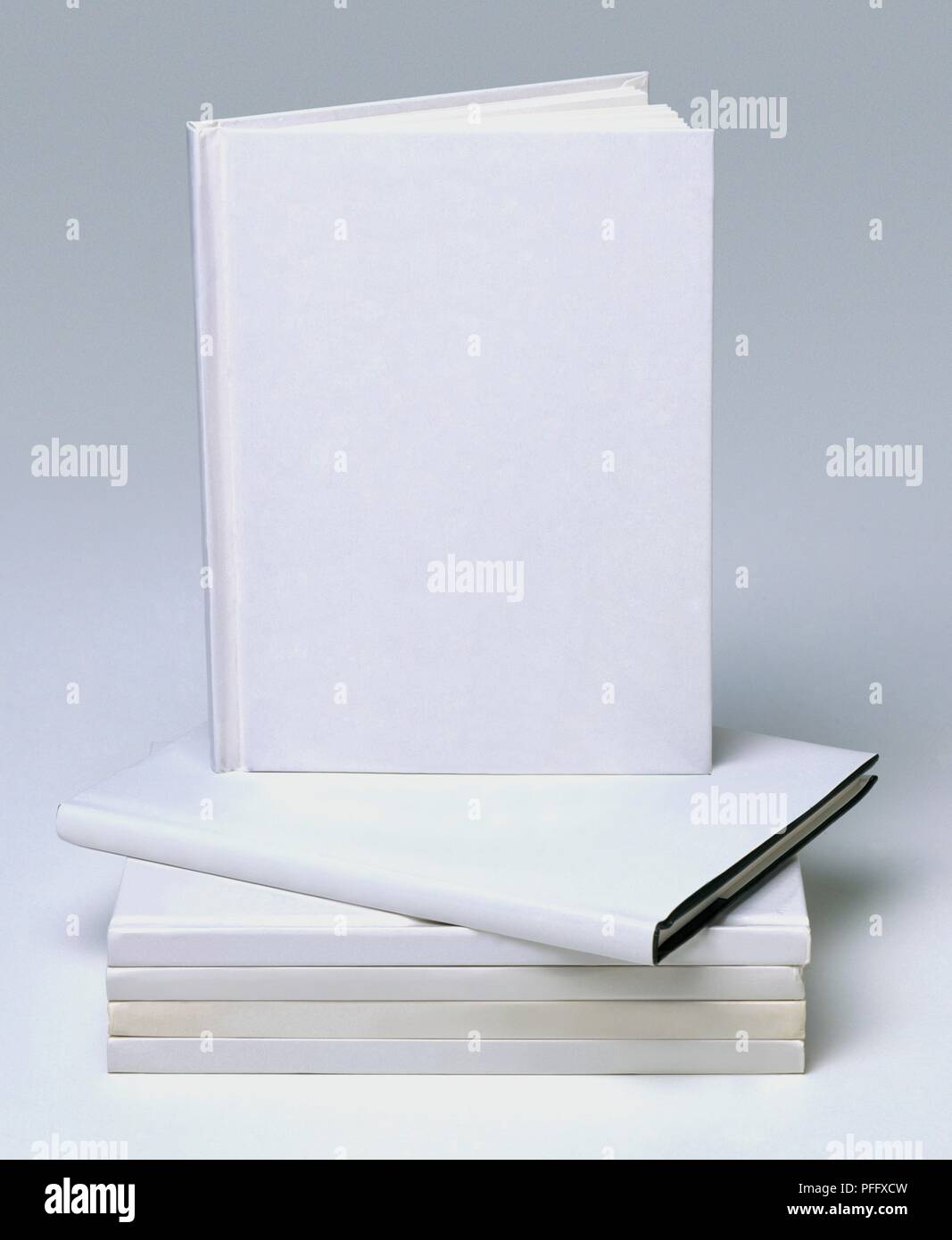 Pila di libri rigida con i coperchi di colore bianco, uno in piedi sulla parte superiore Foto Stock