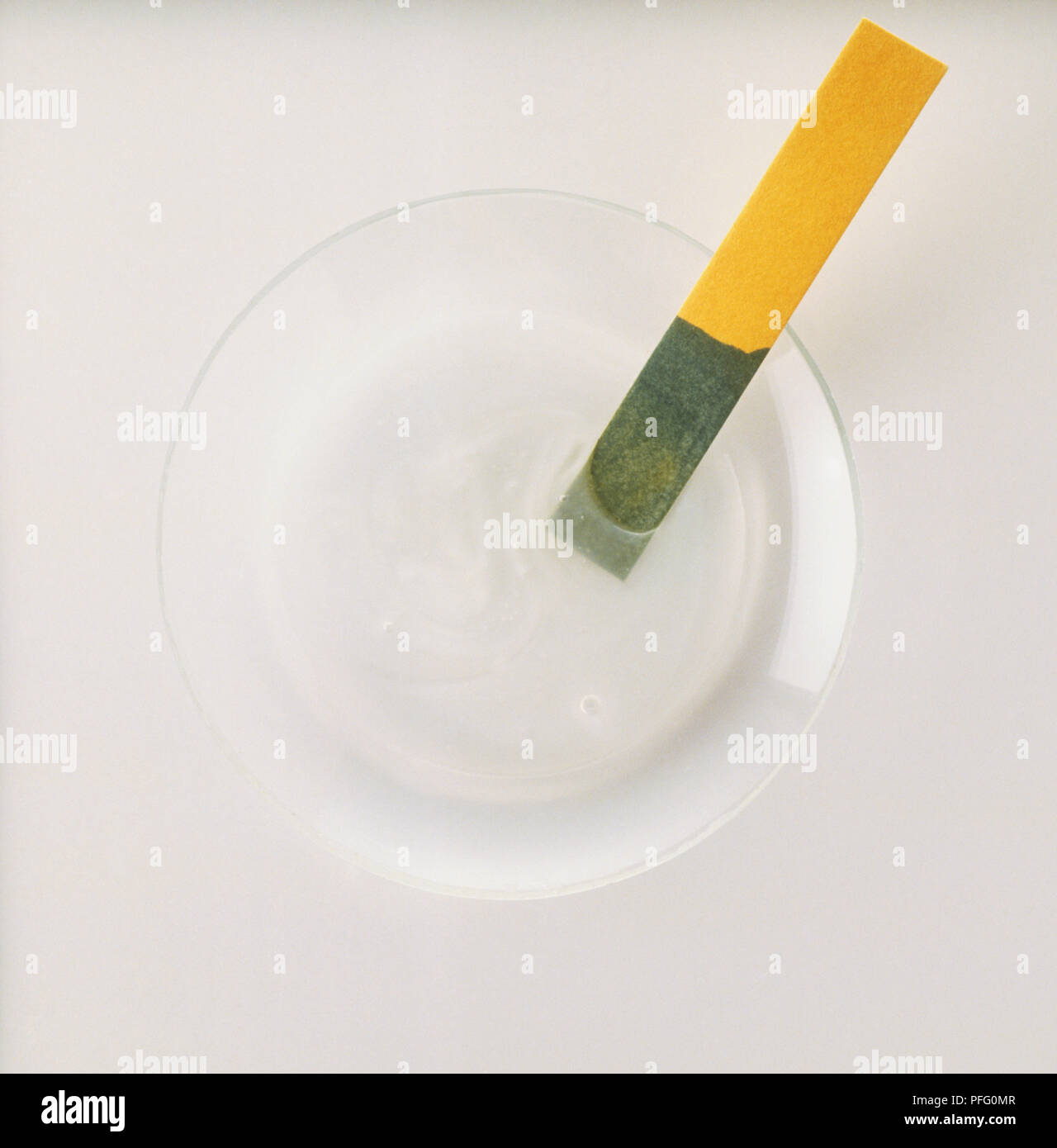 Strisce di tornasole immerso nel detergente domestico di tornitura di liquido verde, vicino. Foto Stock