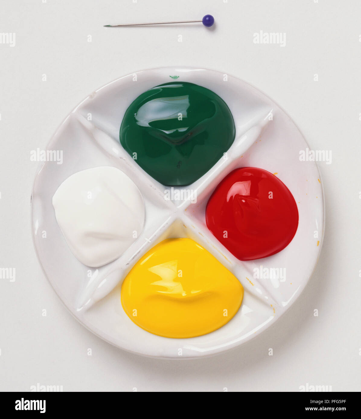 Blob di verde, giallo, rosso e bianco paint nella miscelazione piatto. Foto Stock