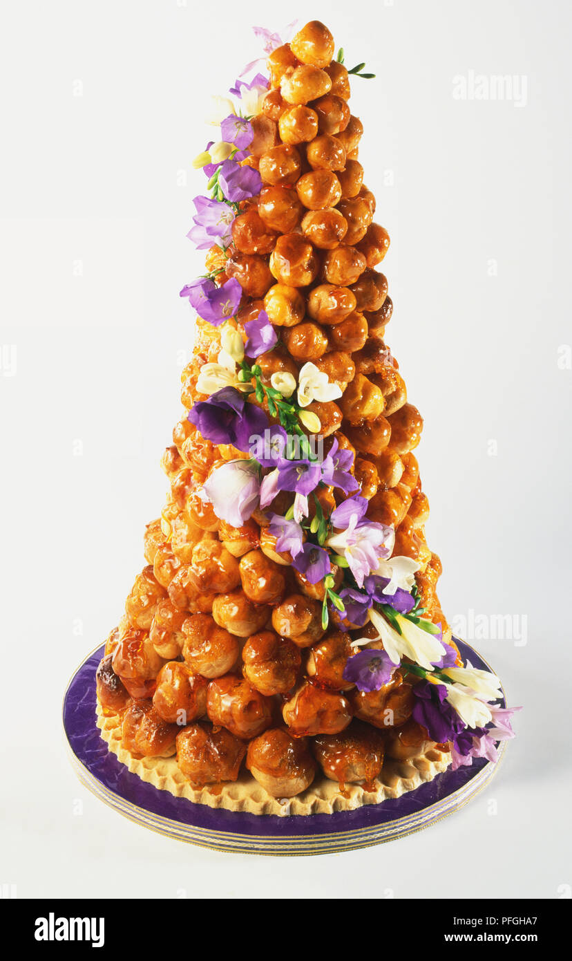 Croquembouche, Francese torta di nozze di bignè riempiti con crema  pasticcera, rivestito con caramello e decorate con piccoli fiori lilla Foto  stock - Alamy