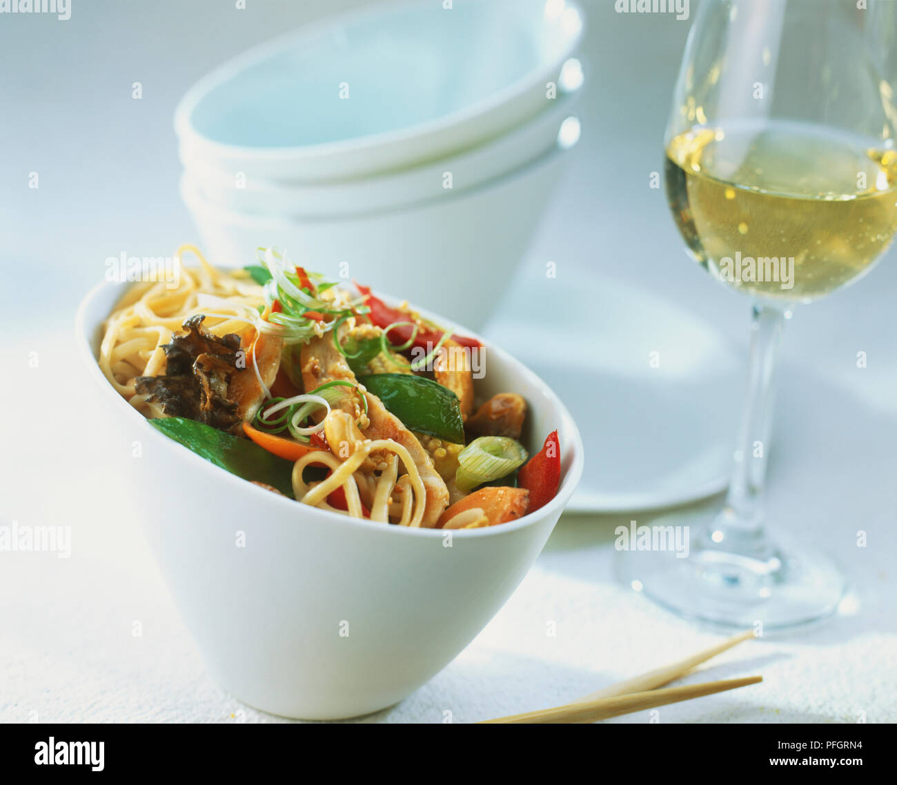 Una ciotola di cibo Cinese e un bicchiere di vino bianco. Foto Stock