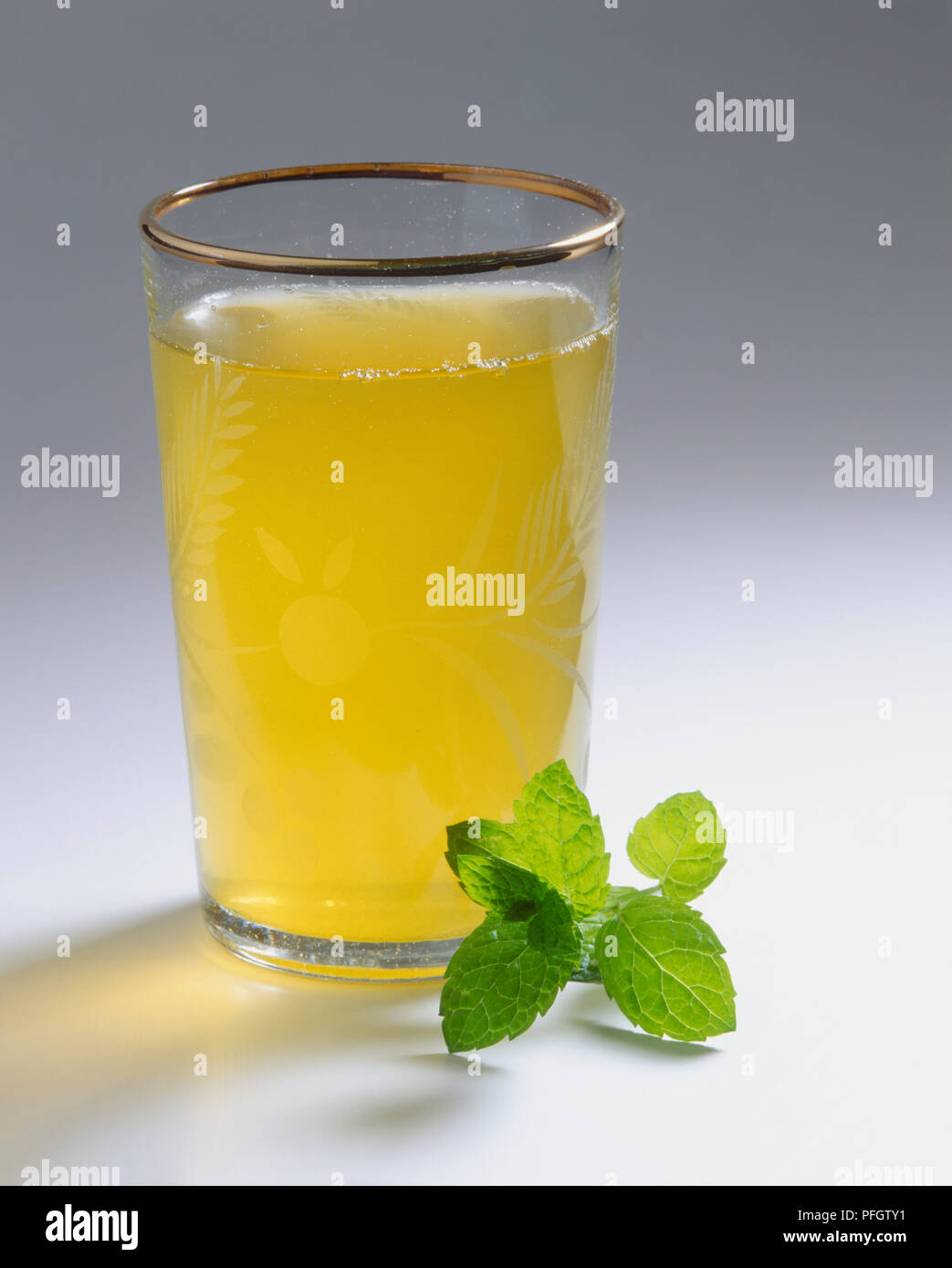 Marocchino tè alla menta in un bicchiere con un rametto di menta accanto Foto Stock