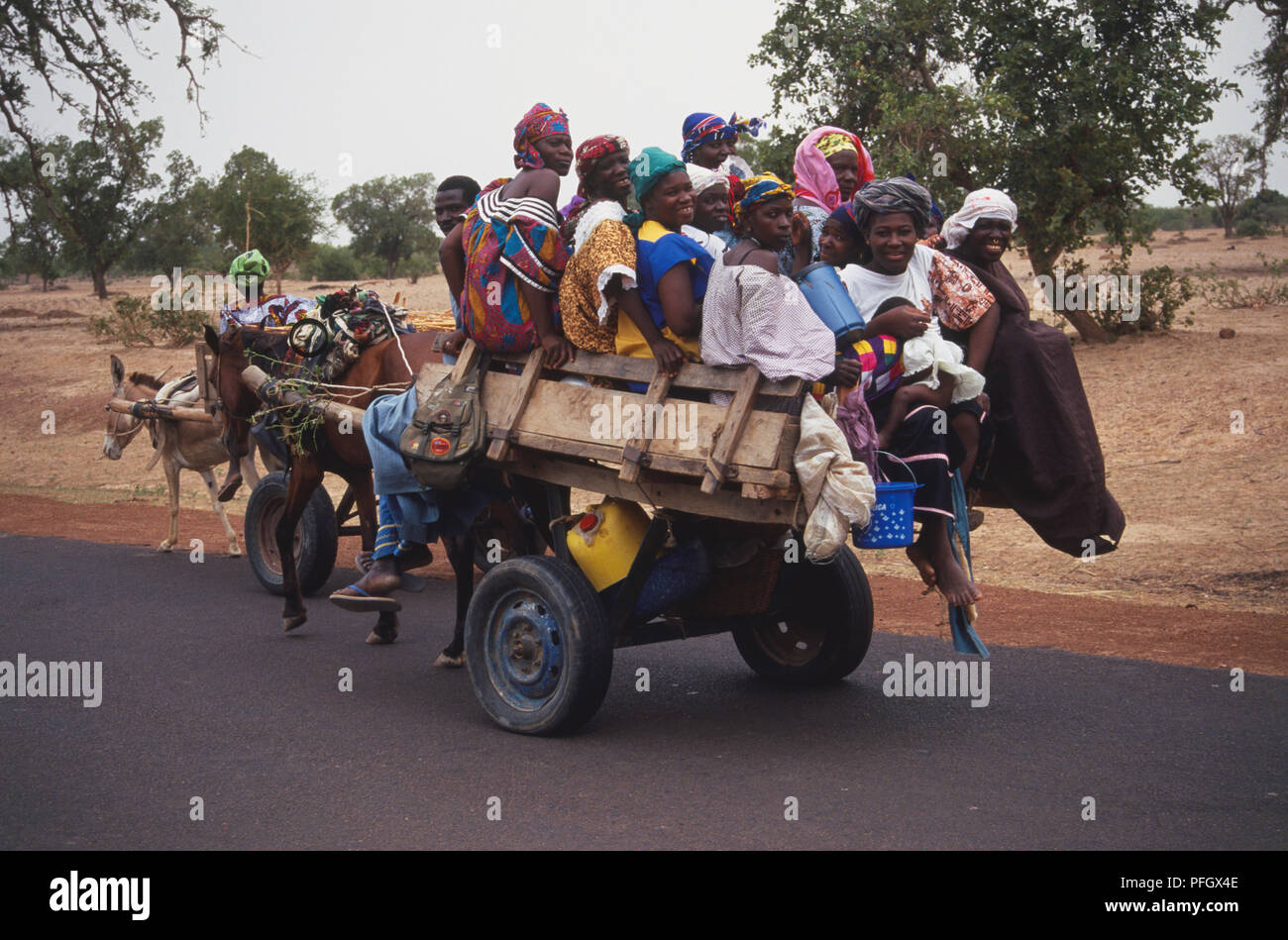 Le donne che vengono trasportati da Horse-Drawn carrello lungo la strada in Africa Foto Stock
